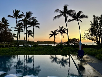 Sunset reflections across the pool and palm trees.