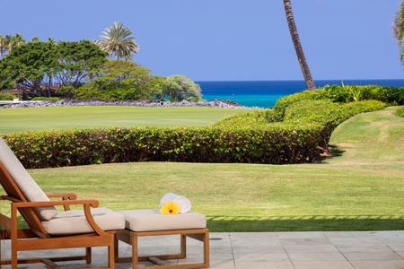 Relax in your elegant living space where floor-to-ceiling windows frame stunning ocean views, creating a seamless indoor-outdoor tropical paradise.