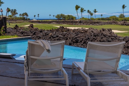 Relax poolside with plentiful seating and picturesque views, ideal for enjoying a serene afternoon.