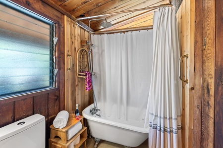 Soak in your vintage clawfoot tub surrounded by rich wood paneling—a charming rustic bathroom where luxury meets mountain cabin charm.