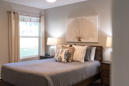 Primary bedroom offers a cozy queen-sized bed and natural light.