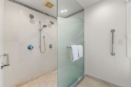 Walk-in rainfall shower with glass enclosure offers a spa-like rinse after beach adventures.