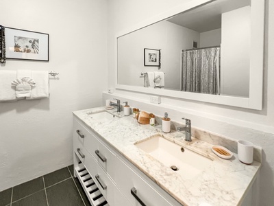 Bright and airy hall bath with a walk-in shower, two vanities and elegant design.