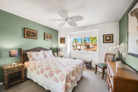 Upstairs guest bedroom features a cozy queen-size bed, ceiling fan, and large windows for restful, breezy nights.