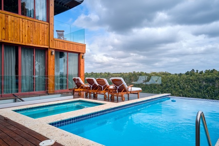 Relax on the chaise loungers by the luxurious infinity pool with stunning forest views.
