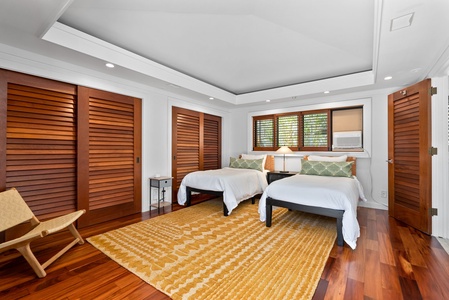 Bright guest bedroom with two twin beds and garden views.