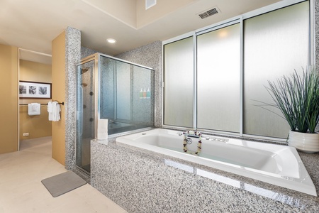 Indulge in your private spa-like bathroom featuring a deep jetted soaking tub and spacious glass shower for ultimate relaxation.