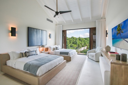 Cozy guest bedroom with two beds and garden views.