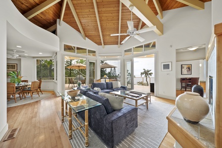 Unwind beneath soaring wood-beam ceilings in this elegant living space, where ocean views flow through floor-to-ceiling windows.