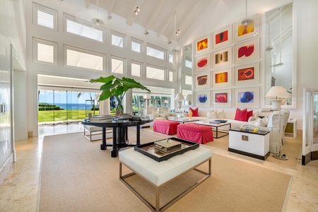 The spacious living room, adorned with colorful artwork, modern furniture, and floor-to-ceiling windows.