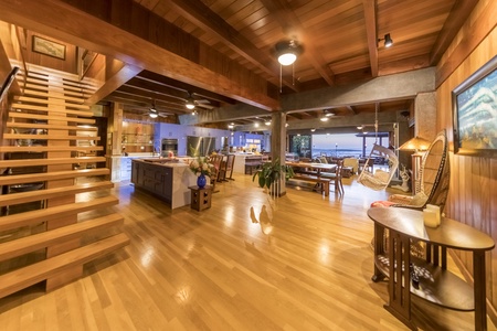 Spacious open-concept living area with a rustic wooden staircase and seamless indoor-outdoor flow