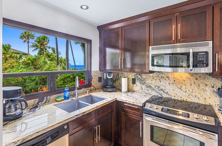 Wailea Ekolu 1605 kitchen features modern appliances and a window with breathtaking ocean and palm views.