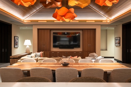 Gather around your grand dining table while enjoying the entertainment center's large screen TV and stunning sculptural lighting overhead.