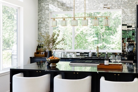 Gather around this stunning kitchen island where golden light filters through windows framing lush greenery. Cook gourmet meals with high-end appliances and elegant finishes surrounding you.