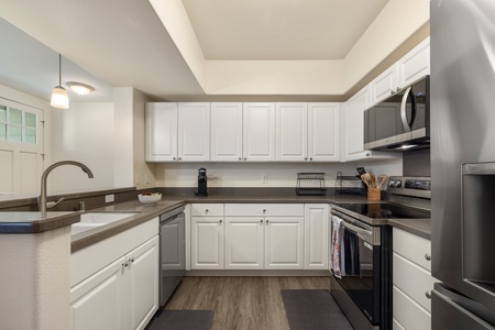 Your fully equipped kitchen features sleek white cabinets, granite countertops, and modern stainless steel appliances ready for culinary adventures.