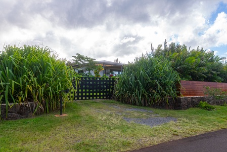 Enter through a charming garden gate bordered by lush greenery and island plantings.