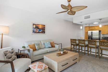 The living area has a chic ambiance with a plush sofa, ceiling fan and central AC, adjacent to the kitchen