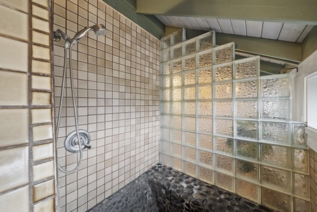 Walk-in shower with glass block design and stone flooring, offering a spa-like retreat.