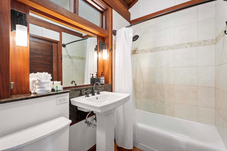 Elegant guest bathroom with a tub, shower, and natural wood details.