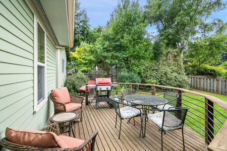 A spacious wooden deck surrounded by greenery allows guests to lounge and soak in the tranquility of the outdoor space.