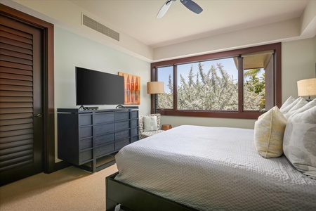 Guest bedroom with modern decor, garden views, and a wall-mounted TV—serene and stylish.
