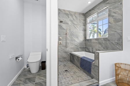 Elegant en-suite layout with full walk-in shower, private toilet nook, and subtle tropical textures.
