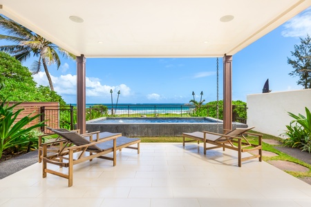 A covered lanai with comfortable loungers, offering tranquil ocean views and a refreshing breeze.