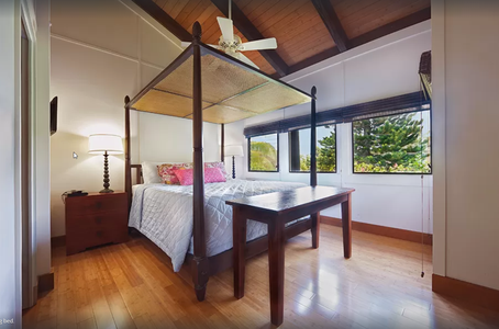Private exterior-access bedroom with four-poster king bed, vaulted ceilings, and garden views.