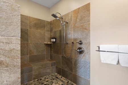 Enjoy a luxurious rinse in the oversized walk-in shower with slate tile and bench seating.