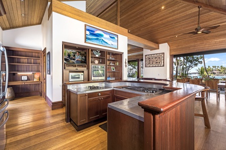 Your chef's paradise features rich wood cabinetry, premium appliances, and stainless steel countertops with tropical views just beyond.