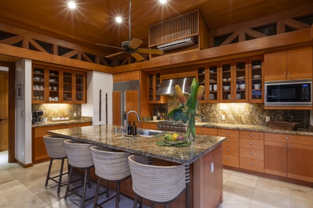 A tranquil view of the dining room, living room, and kitchen, illuminated by tiki torches across the serene pool