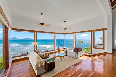 Sink into plush sofas while ocean waves crash just beyond floor-to-ceiling windows in this stunning beachfront living space.