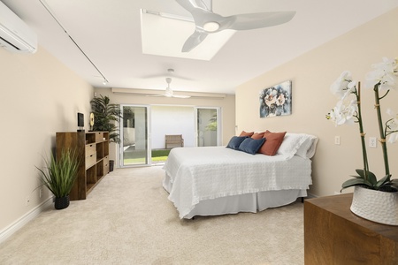 Bright guest suite with queen bed, skylight, and access to the outdoors.