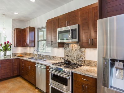 Beautiful custom cabinetry with wood from Indonesia and contemporary stainless steel appliances give this kitchen an island feel.