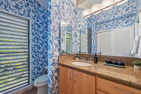Wailea Ekolu 1106 bathroom includes a wide vanity, chic wallpaper, and plenty of natural light.