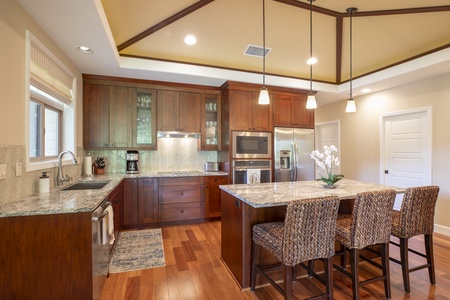 A chef’s dream kitchen awaits, equipped with granite counters, wine fridge, and top-tier appliances.