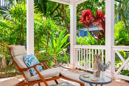 Lush garden surrounds this serene lanai lounge with island-style seating.