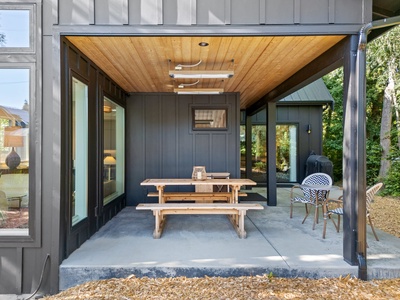 Enjoy all-season dining under a covered patio with picnic seating, patio heaters, and lush backyard views.