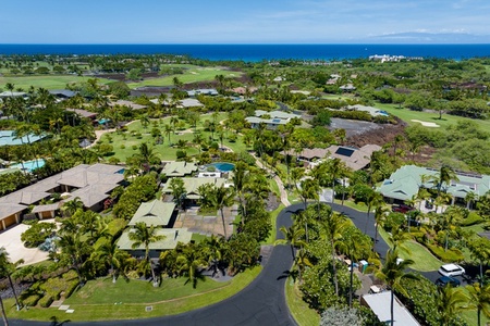 A bird's-eye view of the serene neighborhood surrounded by greenery and ocean views.