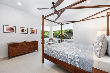 Elegant four-poster king suite with wide windows and tropical art, inviting deep sleep or mid-day siestas in peace.