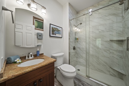 Modern bathroom in studio with walk-in glass shower and granite vanity—style meets function.