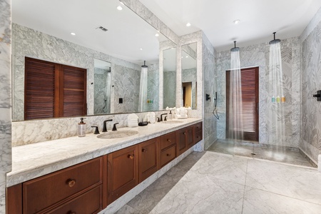 Indulge in your luxurious marble bathroom featuring dual vanities, rainfall showers, and elegant tropical-inspired details for ultimate relaxation.