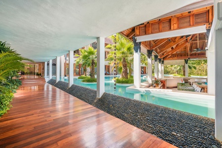 Polished wooden walkway, surrounded by serene water features and lush greenery.