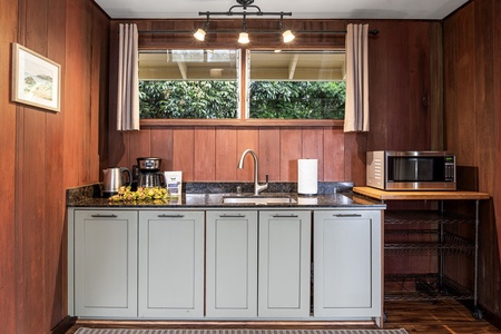 Your kitchenette blends vintage charm with modern conveniences—brew coffee, prepare light meals, and enjoy lush garden views through the sunlit windows above the sink.
