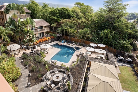 Expansive pool area surrounded by lush greenery, with ample seating for lounging and relaxing.