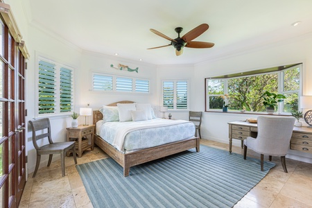 Primary bedroom with king bed, ceiling fan, and tranquil golf course views — a peaceful space to unwind.