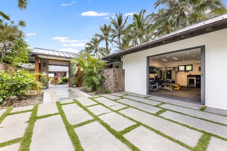 Garage and private gym access tucked behind tropical foliage for a discreet entrance.