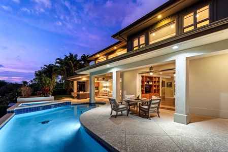 Elegant outdoor dining and pool area illuminated for tranquil evening relaxation.