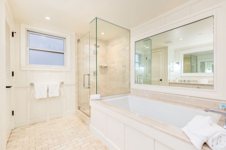 Primary bathroom features glass shower, soaking tub, and natural stone finishes.