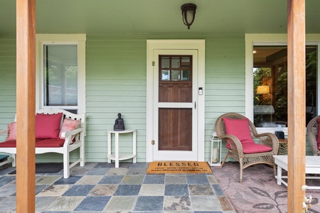 Welcome guests through the inviting front door and onto a charming slate-tiled porch with cozy seating for enjoying the peaceful surroundings.